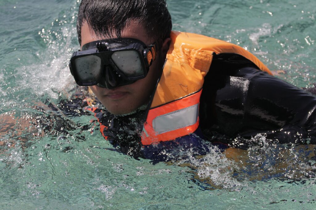 Crop  man in swimming vest and goggles in seawater